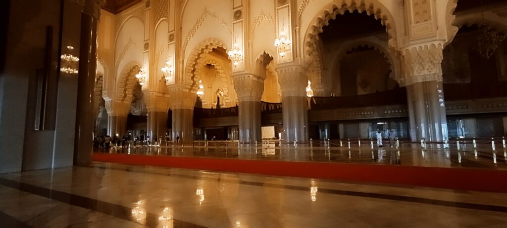 A mosque prayer hall with chandeliers and carved arches