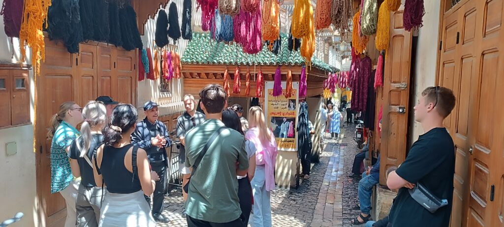 A group in a souk hung with dyed wool