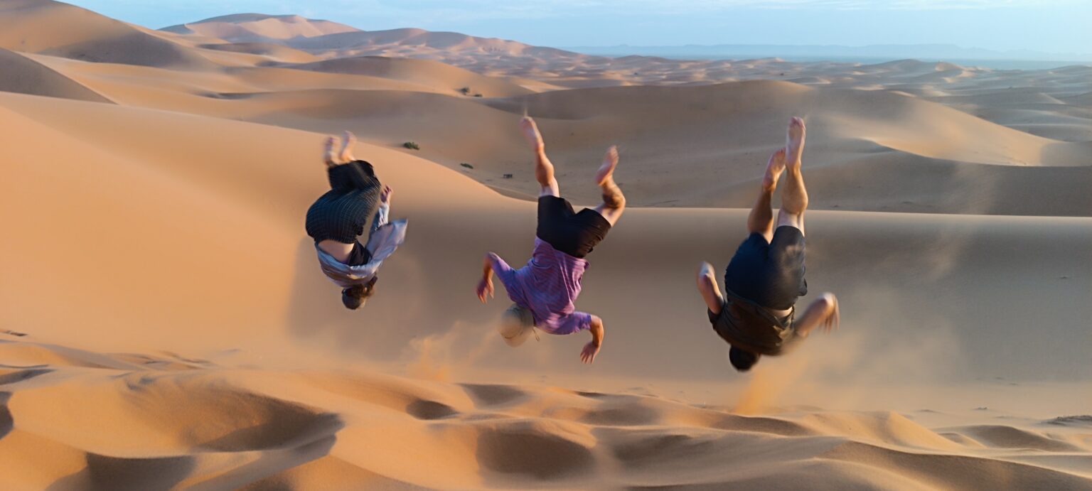 Three people jumping off a sand dune
