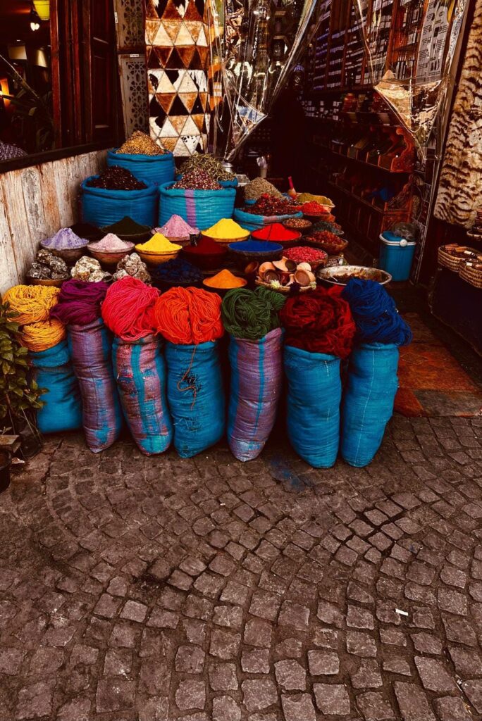 Bowls of coloured dye powders, spices and skeins of wool outside a souk shop